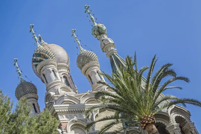 Blick auf die Türme der Chiesa San Basilio vor blauem Himmel mit Palme, Sanremo, Ligurien Italien