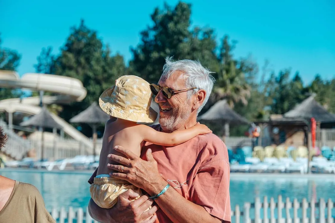Grand-père avec un enfant au bord de la piscine des Méditerranées à Marseillan-Plage
