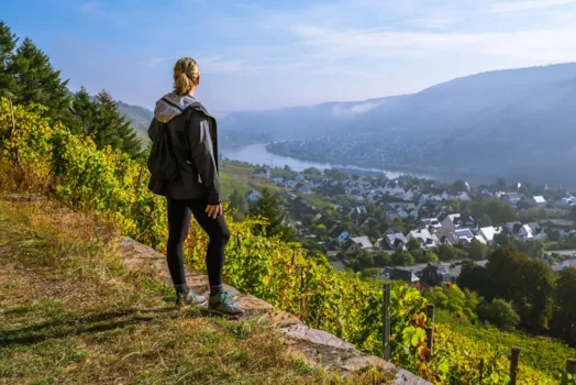 Eine Wanderin genießt den Blick über Weinberge und den Rhein nahe der Stadt Winningen, Deutschland
