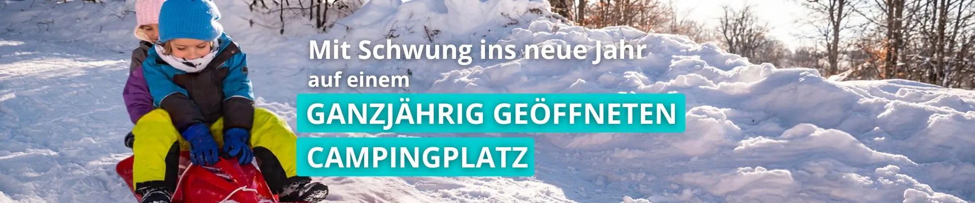 Zwei Kinder auf einem Schlitten sausen einen Waldweg hinunter