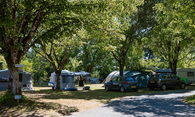 Emplacement camping avec voiture, tente et caravane